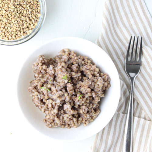 Bowl of cooked buckwheat with a striped napkin and a fork.