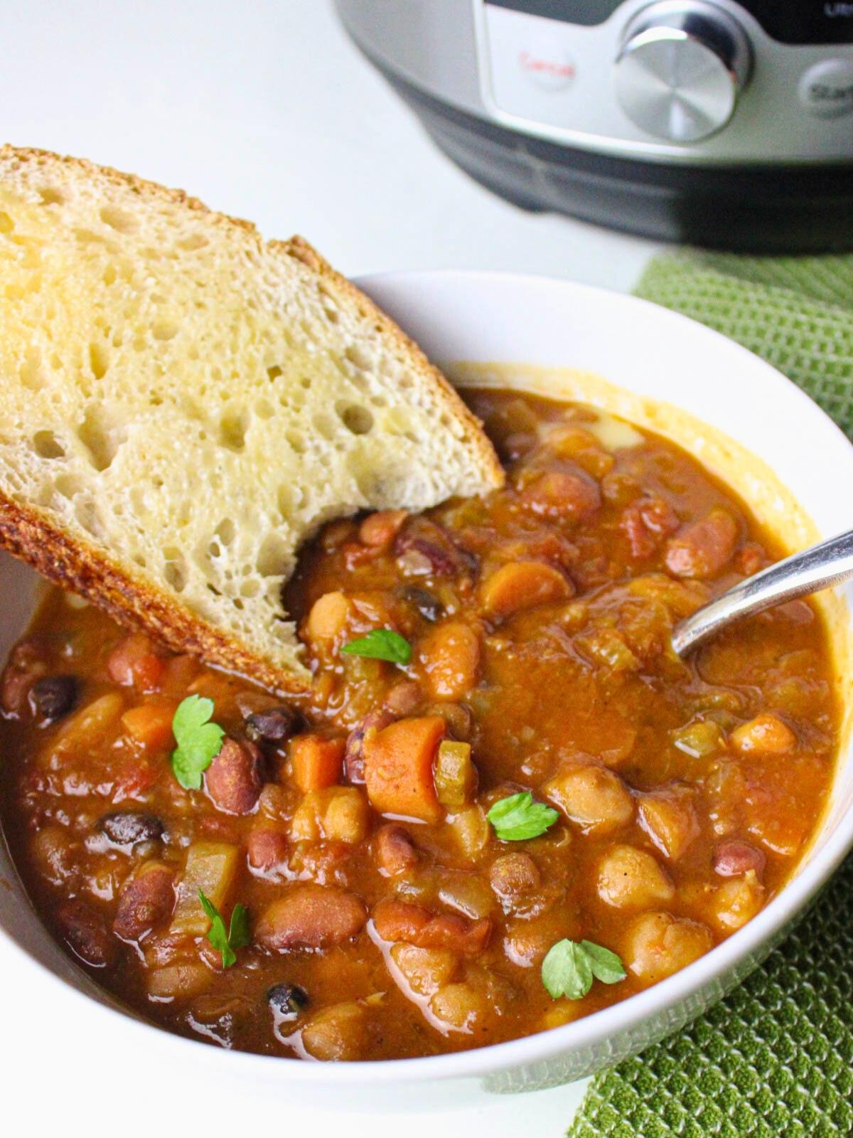 A bowl of 15 bean soup, garnished with fresh parsley, and toasted sourdough bread.