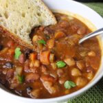 A bowl of 15 bean soup, garnished with fresh parsley, and toasted sourdough bread.